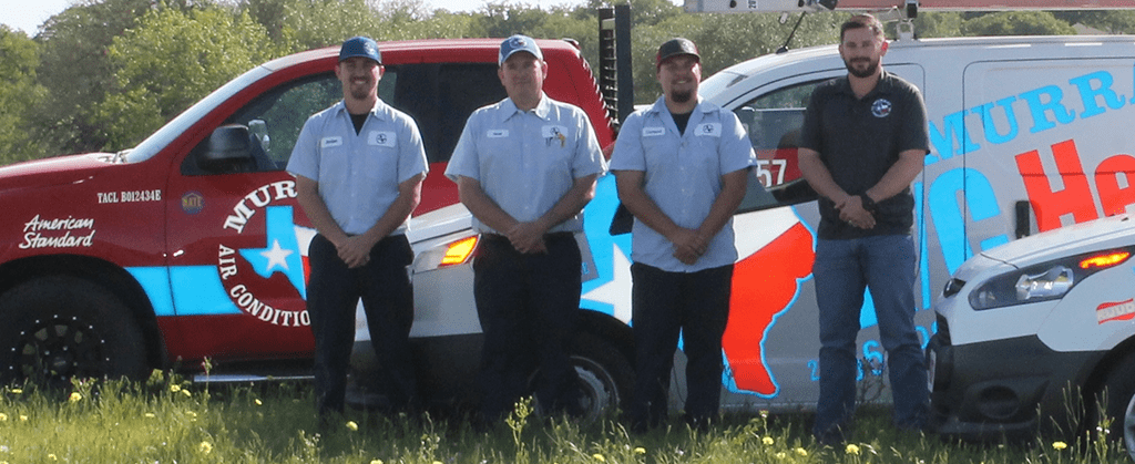Four technicians standing in front of their company vehicles