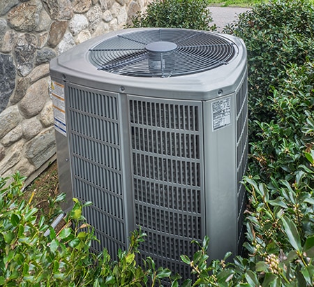 Gray air conditioner in a bush