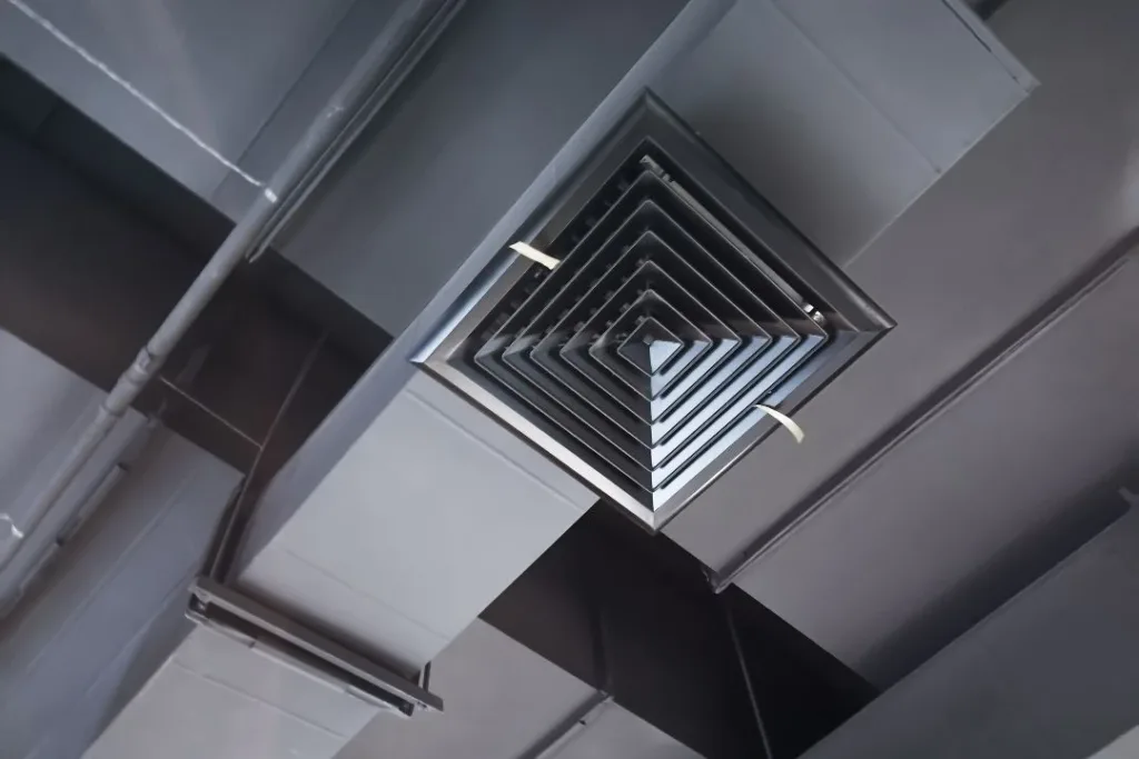 A close-up view of a square ceiling air vent with a modern design