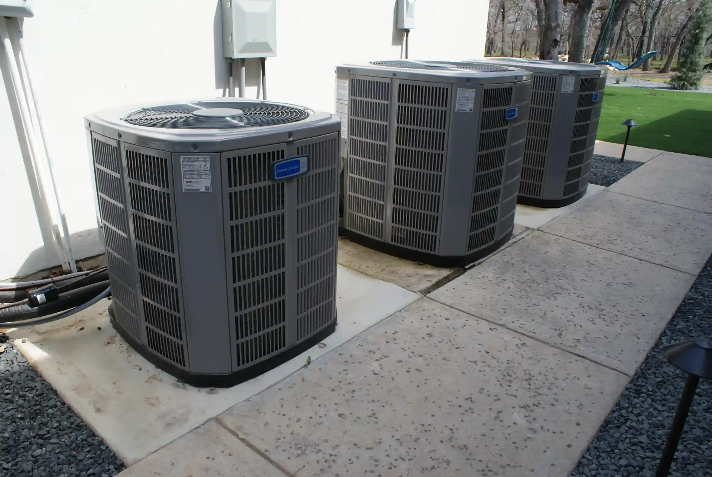Commercial services available. Three large outdoor air conditioning units are installed side by side on concrete pads