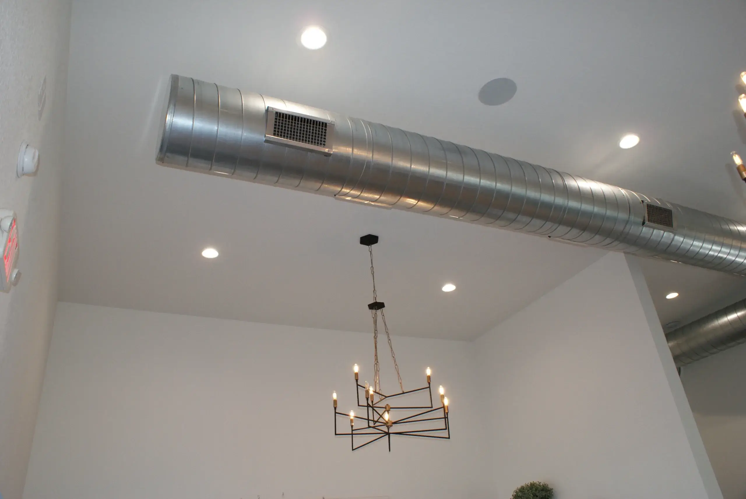 Interior view of a ceiling with an exposed metal air duct running horizontally across the room.