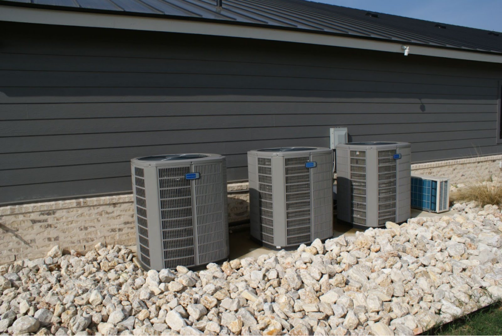 Outdoor air conditioning units placed beside a building with a gravel base.