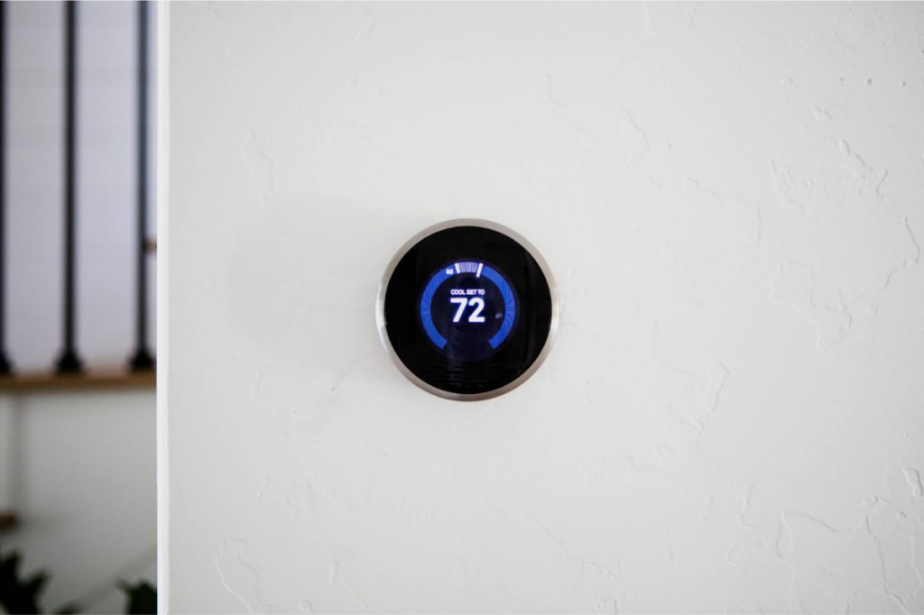 A smart thermostat mounted on a white wall.