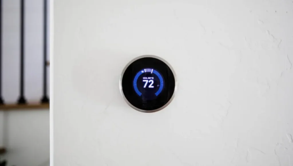 A smart thermostat mounted on a white wall.