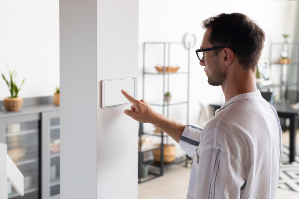 Man adjusting a smart thermostat on a wall.