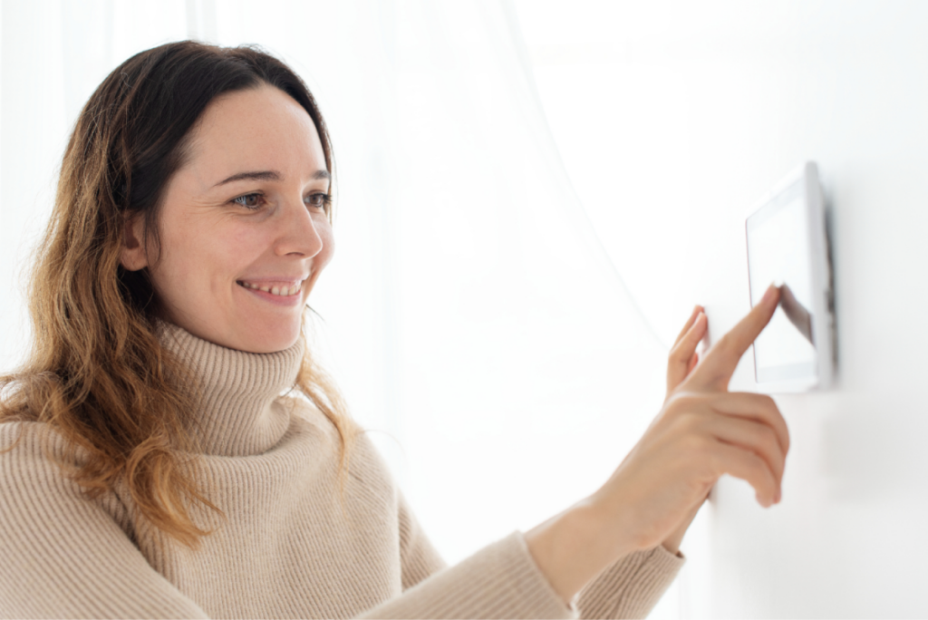 Woman adjusting a digital thermostat on the wall.