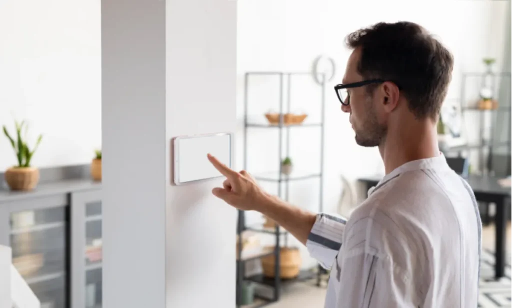 Man adjusting a smart thermostat on a wall.